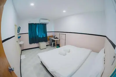 a hospital room with a white bed and a blue curtain at XX Mitr Inn Phuket Oldtown in Phuket Town