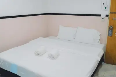 a white bed with two white pillows on it at XX Mitr Inn Phuket Oldtown in Phuket Town