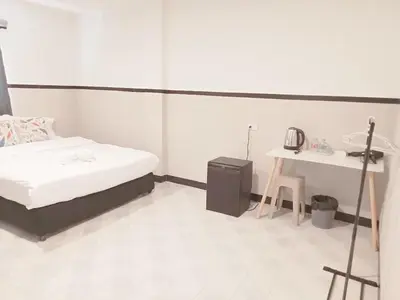 a white room with a bed and a table at XX Mitr Inn Phuket Oldtown in Phuket Town