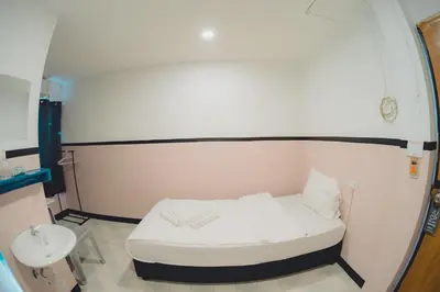 a small room with a white bed and a sink at XX Mitr Inn Phuket Oldtown in Phuket Town