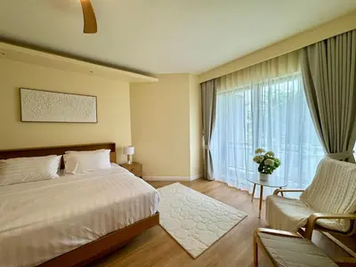 a bedroom with a bed and a chair and a window at Cozy 1 BR Allamanda Laguna Phuket in Laguna Phuket