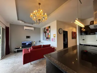 a living room with a red couch and a chandelier at Tropical 2BR Villa Sunset & Sea View in Karon Beach
