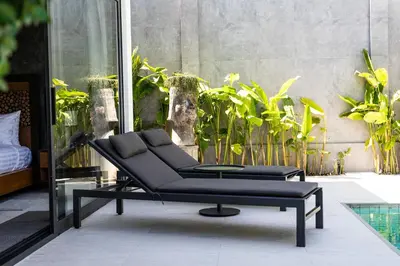 a black couch sitting on a patio with plants at Andaman Paradise 2 Luxury 4 Bedrooms Pool Villa in Rawai Beach
