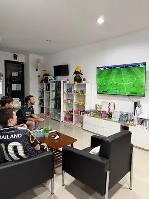 a group of people sitting in a room playing a video game at Global Beach Hostel - Ao Nang in Ban Khlong Haeng
