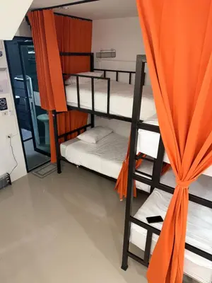 a dorm room with bunk beds and an orange curtain at Global Beach Hostel - Ao Nang in Ban Khlong Haeng