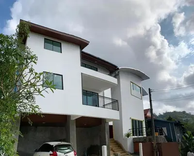 a white house with a car parked in front of it at Hillside 3 Bedroom Vacation Home with Pool in Kamala Beach