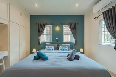 a bedroom with a large bed with two blue pillows at Areca Holiday Home 7, Bangtao Beach in Ban Thalat Choeng Thale