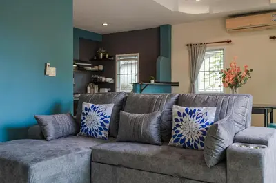 a gray couch with pillows in a living room at Areca Holiday Home 7, Bangtao Beach in Ban Thalat Choeng Thale