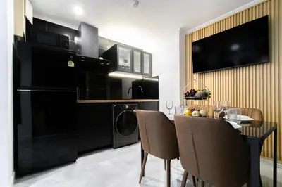 a kitchen with a black refrigerator and a table with chairs at Patong Tower 2 Bedroom Sea View 8 Floor in Patong Beach