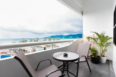 a balcony with a table and chairs and the ocean at Patong Tower 2 Bedroom Sea View 8 Floor in Patong Beach