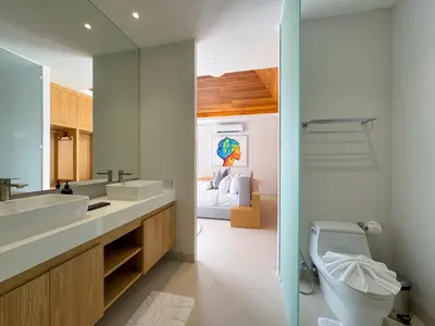 a bathroom with two sinks and a toilet and a bedroom at Sumptuous Duplex Pool Villa 3BR in Newly Built LuxPride 4 L12 Residence in Bang Tao Beach