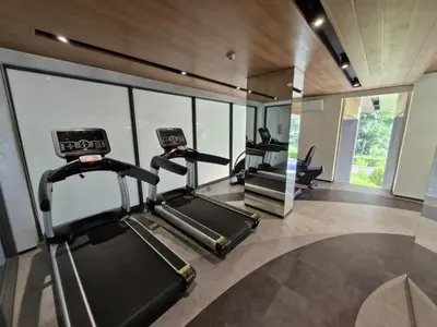a gym with three treadmills in a room with windows at Laguna Song in Bang Tao Beach