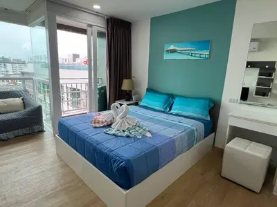 a bedroom with a bed with blue sheets and a balcony at OZONE Best Studio After Renovation 2025 in Kata Beach