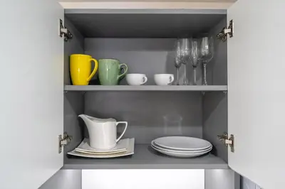 a cupboard with plates and utensils in it at Studio Apartment - Nakalay Palm in Kamala Beach