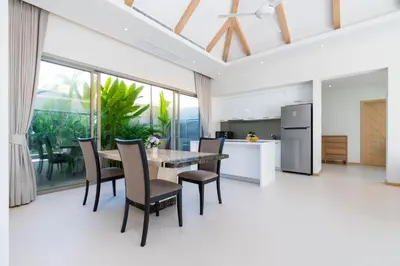 an open kitchen and dining room with a table and chairs at Trichada Tropical - 3 Bedrooms Pool Villa in Laguna Phuket