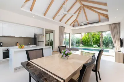 a kitchen and dining room with a wooden table and chairs at Trichada Tropical - 3 Bedrooms Pool Villa in Laguna Phuket