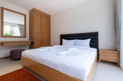 a bedroom with a large white bed with a mirror at Trichada Tropical - 3 Bedrooms Pool Villa in Laguna Phuket