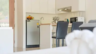 a kitchen with a refrigerator and a table with chairs at Mountain Loft 700m from Beach [Pool & Gym] in Karon Beach