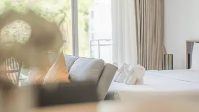 a woman sitting on a couch in a hotel room at Mountain Loft 700m from Beach [Pool & Gym] in Karon Beach