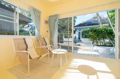 a living room with a table and chairs and a large window at Loft with pool - 8min walk to Rawai Beach - 