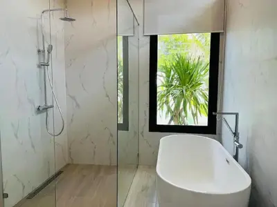 a bathroom with a white tub and a glass shower at Joy Villa - Luxury 4 bedroom villa in Ban Saiyuan (1)