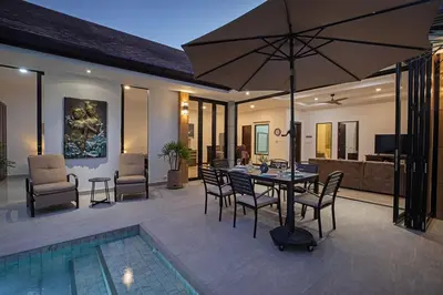 a patio with a table and chairs and an umbrella at La Ferme Villa - Modern 3 Bedrooms with Private Pool in Rawai Beach