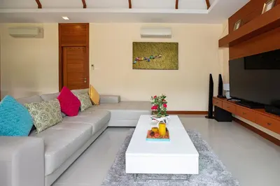 a living room with a couch and a tv at Orchid Villa - 3 Bedrooms Pool Villa - Rawai beach in Rawai Beach