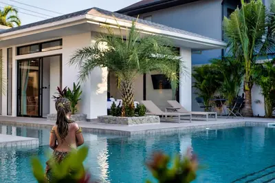 a woman standing in front of a house with a swimming pool at Palm Villa - Spacious 4 Bedrooms with Private Pool in Rawai Beach