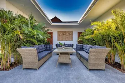a patio with couches and a table and palm trees at Palm Villa - Spacious 4 Bedrooms with Private Pool in Rawai Beach