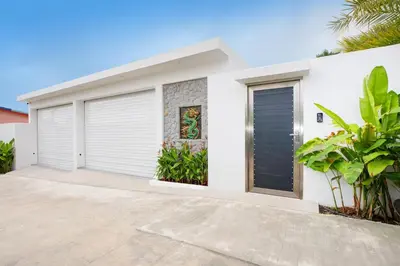 a white house with two garage doors at Pattana Moon - Luxury Calm 4 Bedrooms Pool Villa in Ban Saiyuan (1)