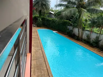a blue swimming pool on the side of a building at Cozy Condotel Maikhao in Mai Khao Beach