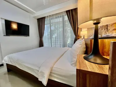 a bedroom with a white bed and a window at Cozy Condotel Maikhao in Mai Khao Beach
