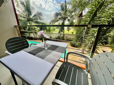 a table and chairs on a balcony with palm trees at Cozy Condotel Maikhao in Mai Khao Beach