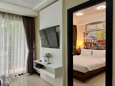 a bedroom with a bed and a flat screen tv at Cozy Condotel Maikhao in Mai Khao Beach
