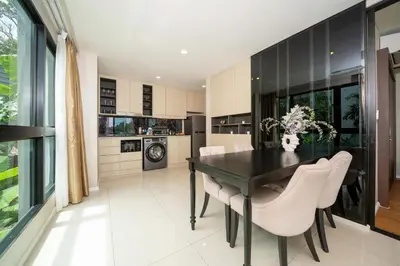 a dining room with a black table and white chairs at Deluxe Surin apartment with washer and fast WIFI in Surin Beach