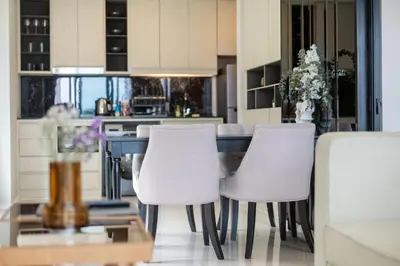 a kitchen with white chairs and a table at Deluxe Surin apartment with washer and fast WIFI in Surin Beach