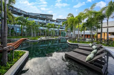 a resort with a pool with palm trees and a building at Deluxe Surin apartment with washer and fast WIFI in Surin Beach