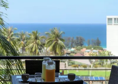 a table with two bottles of orange juice on a balcony at Karon beach Stylish large 2BR with Sea View in Karon Beach