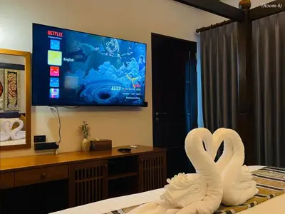two swans sitting on top of a bed with a tv at Kiri Anda Villa Phuket in Rawai Beach
