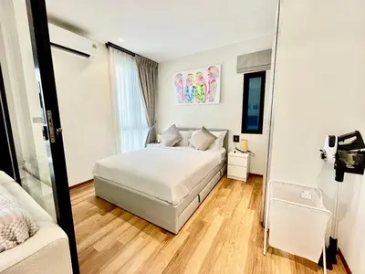 a white bedroom with a bed and a mirror at Title HALO 1 - Modern 1BR Pool View Walk to Nai Yang Beach in Nai Yang Beach