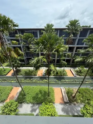 a courtyard with palm trees in front of a building at Baan Mai Khao beachfront apartments in Mai Khao Beach