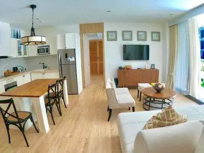 a kitchen and living room with a table and a couch at Baan Mai Khao beachfront apartments in Mai Khao Beach