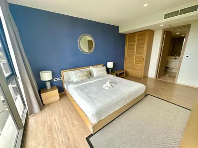 a bedroom with a large bed with a blue wall at Baan Mai Khao beachfront apartments in Mai Khao Beach