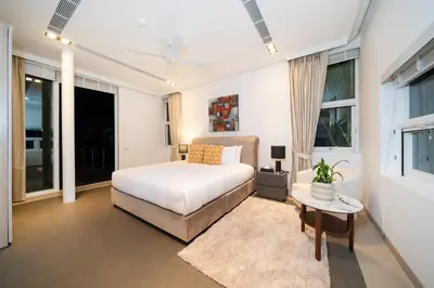 a bedroom with a bed and a table and windows at The bay Cape Yamu Villa 10 in Phuket Town