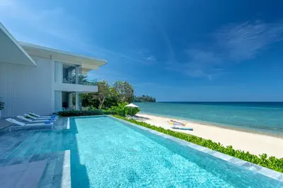 a swimming pool next to a beach next to a house at Villa ANDA in Kamala Beach