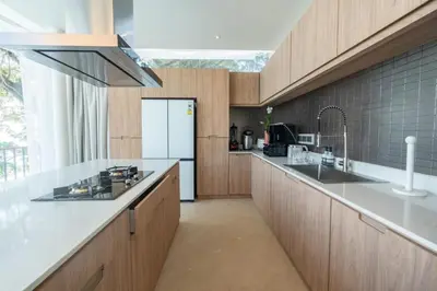 a kitchen with wooden cabinets and a white refrigerator at The bay Cape Yamu Villa 2 in Ko Lek