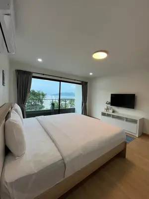 a bedroom with a large white bed and a television at Hill Bay Suites Hotel in Patong Beach