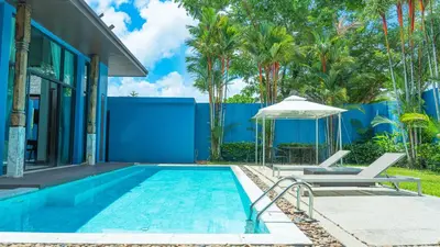 a swimming pool next to a house with a blue wall at Bangtao Beach 3 bedroom private pool villa in a quiet area near Boat Avenue mono wings in Bang Tao Beach