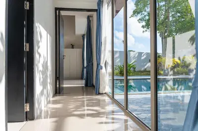 a hallway with sliding glass doors leading to a swimming pool at Bang Tao 6-bedroom large private pool modern Balinese style leisure holiday villa BBQ family group the park in Bang Tao Beach