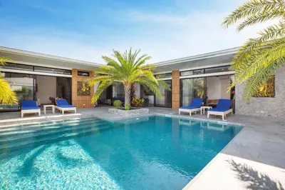 a swimming pool with blue chairs and a house at Pattana Sun Villa - Modern 4 Bedrooms Villa with Pool in Ban Saiyuan (1)